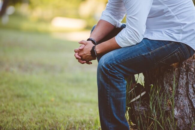 man in white shirt and jeans sitting