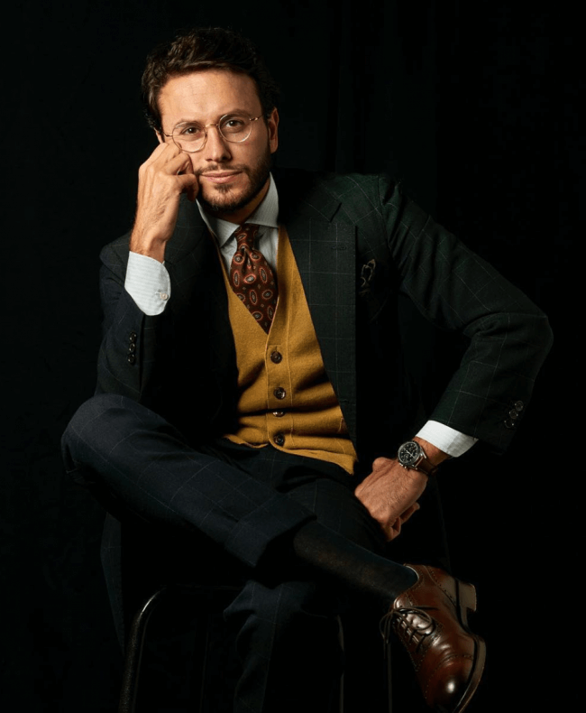 man posing in brown vest and black suit