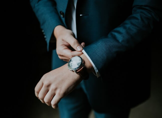 man in suit buttoning up sleeves