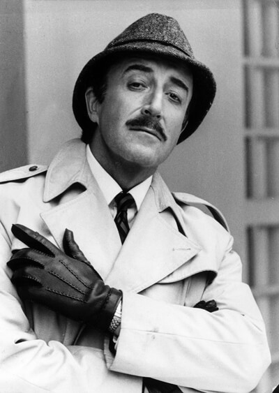 Peter Sellers as Inspector Clouseau in his legendary outfit of trench coat and trilby tweed hat.