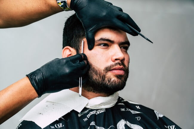 man trimming beard with a razor