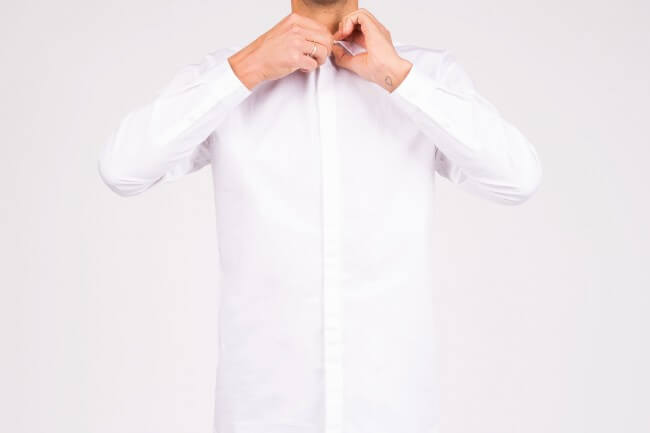 man buttoning up shirt